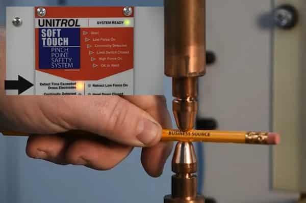 hand holding pencil in between two spot welding electrodes